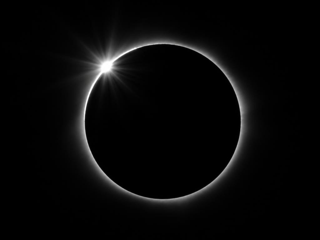 Total solar eclipse at the diamond ring moment: a black disc with one point of light breaking the rim